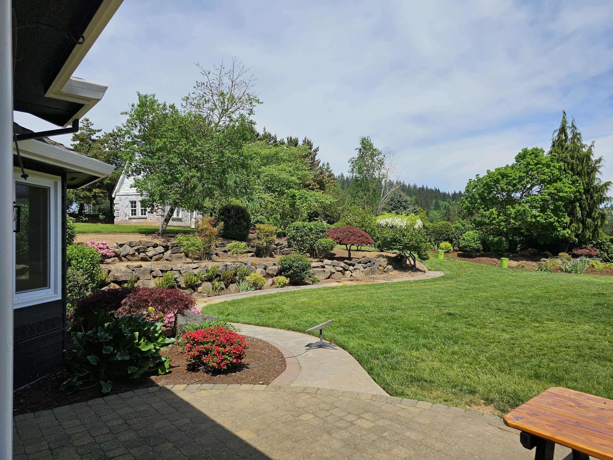 A large landscaped backyard with a stone retaining wall and expansive lawn